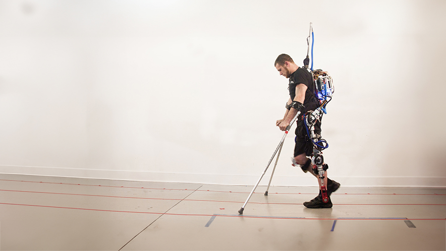 Individual using advanced robotic exoskeleton technology for mobility assistance, supported by crutches in a minimalistic indoor setting