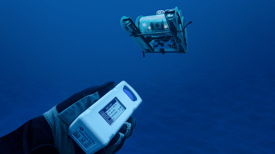 An underwater scene showing a remotely operated vehicle (ROV) suspended in blue water